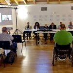 Sala conferenze con partecipanti seduti di fronte a un tavolo di relatori; sullo sfondo uno schermo proietta una videoconferenza con interprete LIS. L’evento è la conferenza stampa di presentazione di Accessibility for Future 2025, svoltasi a Udine Esposizioni.